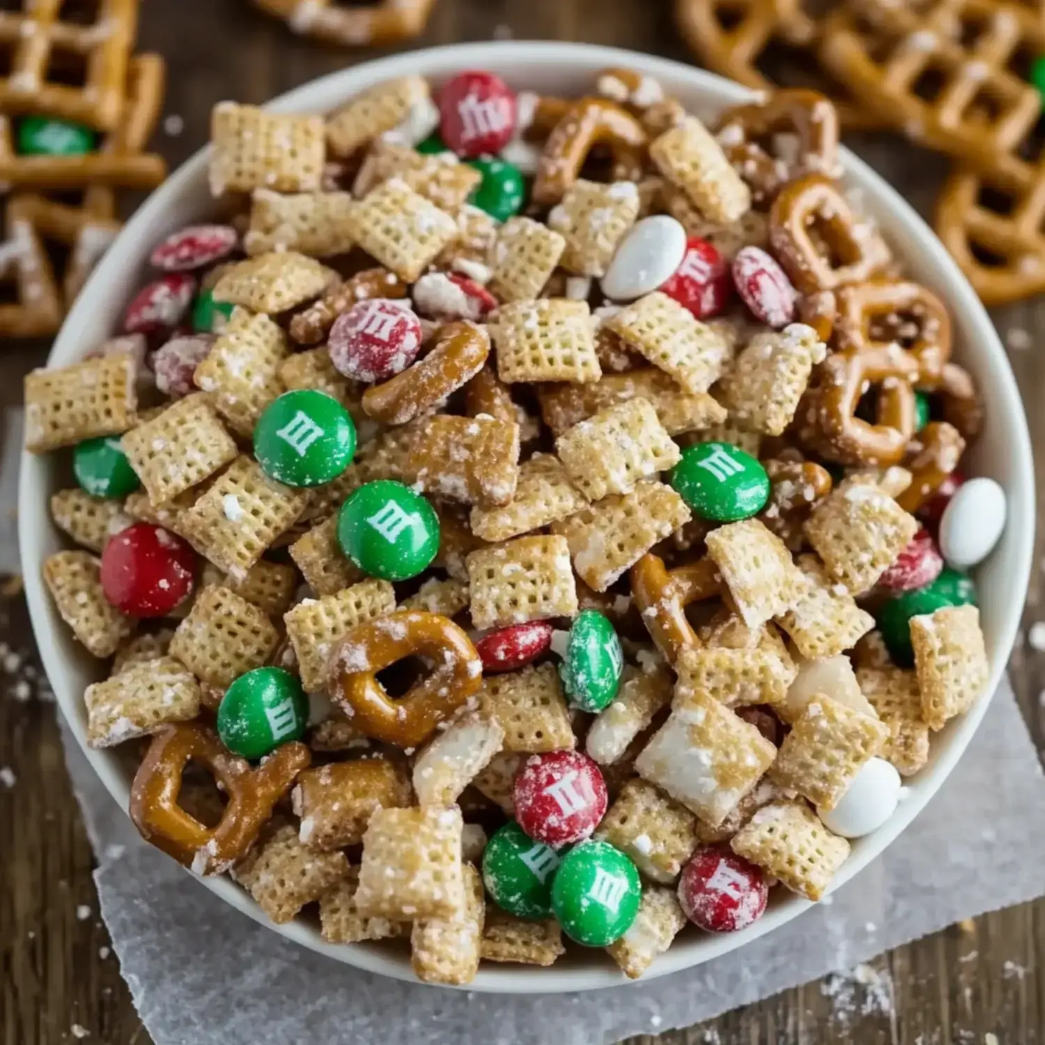 A festive bowl filled with cereal mix, pretzels, and bright M&Ms.