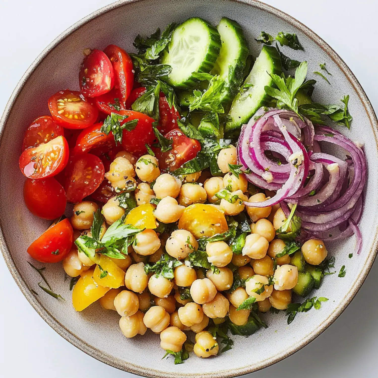 A colorful blend of chickpeas, cucumbers, tomatoes, red onions, and parsley in a bowl.