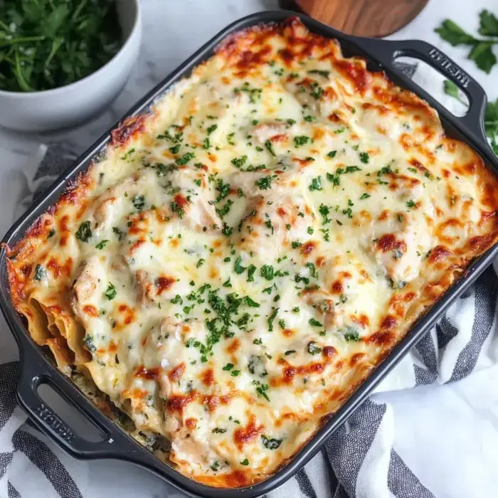 A bubbling lasagna with melted cheese and parsley, served in a black dish.