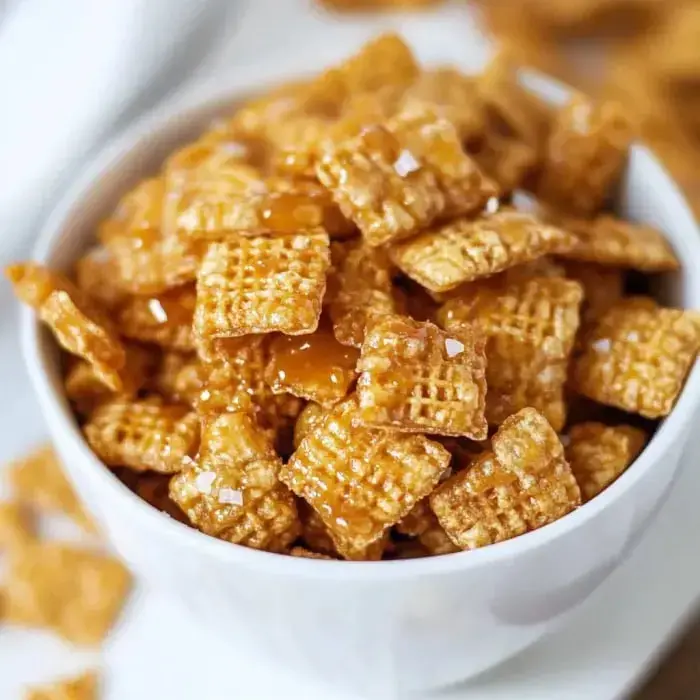 Golden crunchy Crispix pieces coated in rich caramel, sprinkled with sea salt in a bowl.