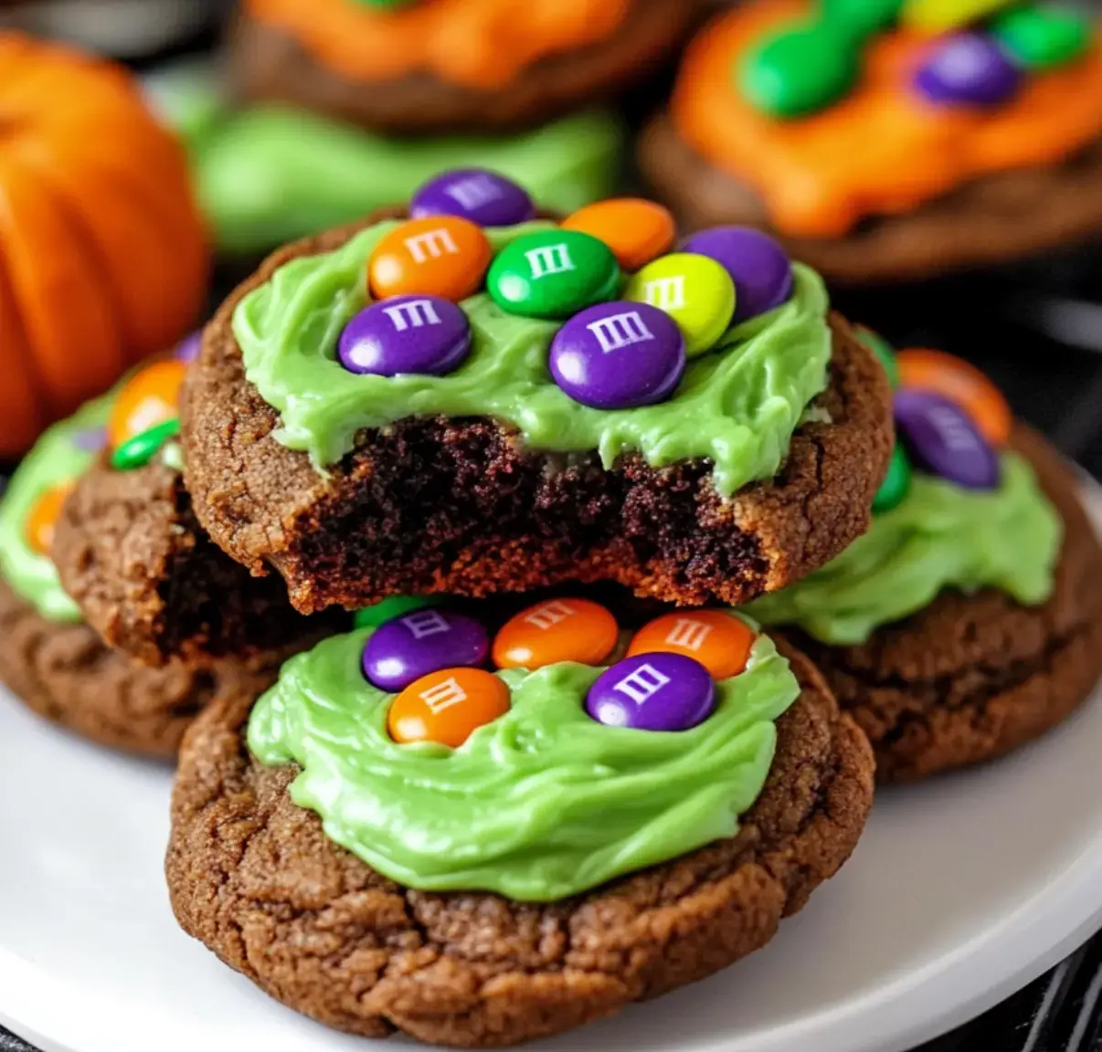 A plate of fudgy cookies with bright green frosting inside, decorated with colorful candies for a Halloween vibe.