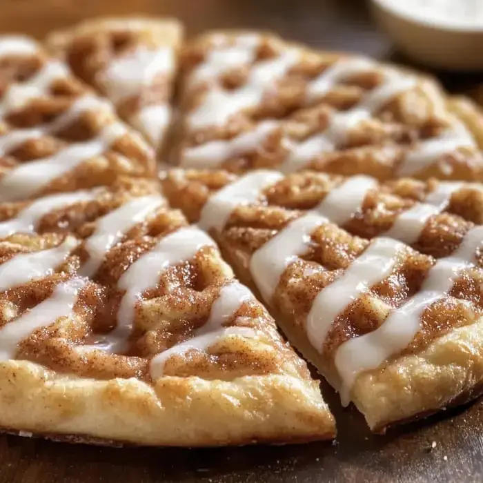Triangular cuts of cinnamon-topped dough drizzled with glaze on a rustic board.