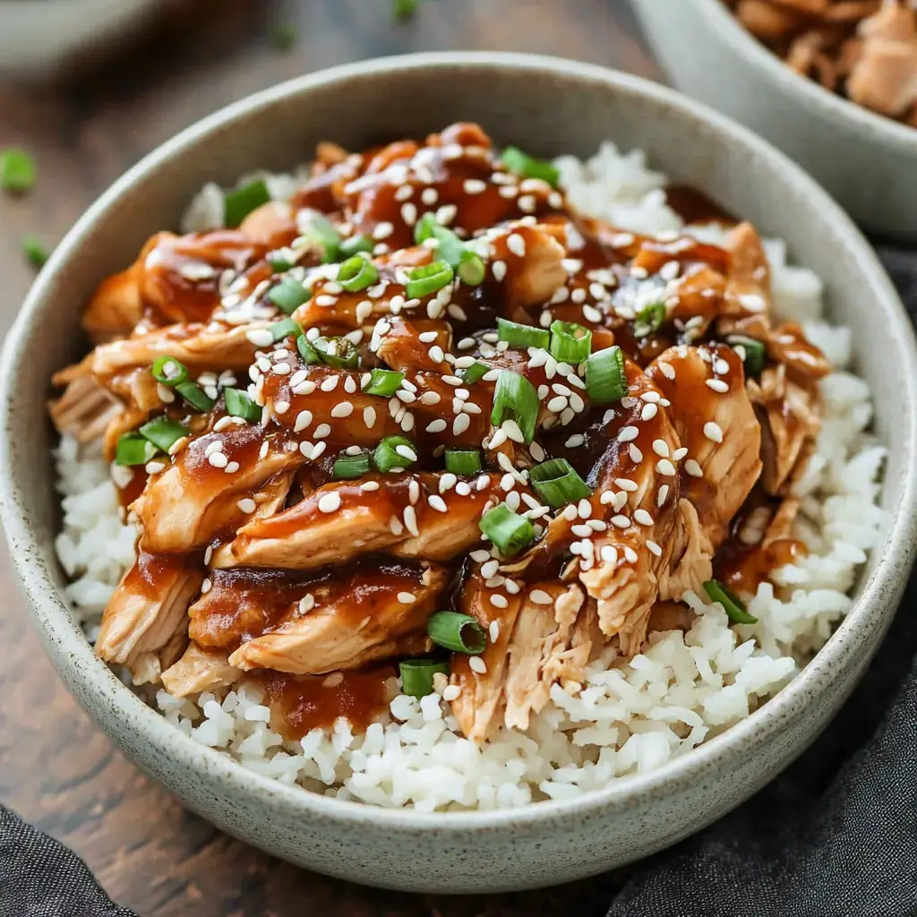 Shredded chicken on white rice, topped with sesame seeds and sliced green onions. Warm teriyaki sauce drizzled over.