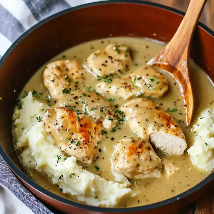Creamy chicken with savory gravy and tender chicken layered on fluffy mashed potatoes, topped with herbs.