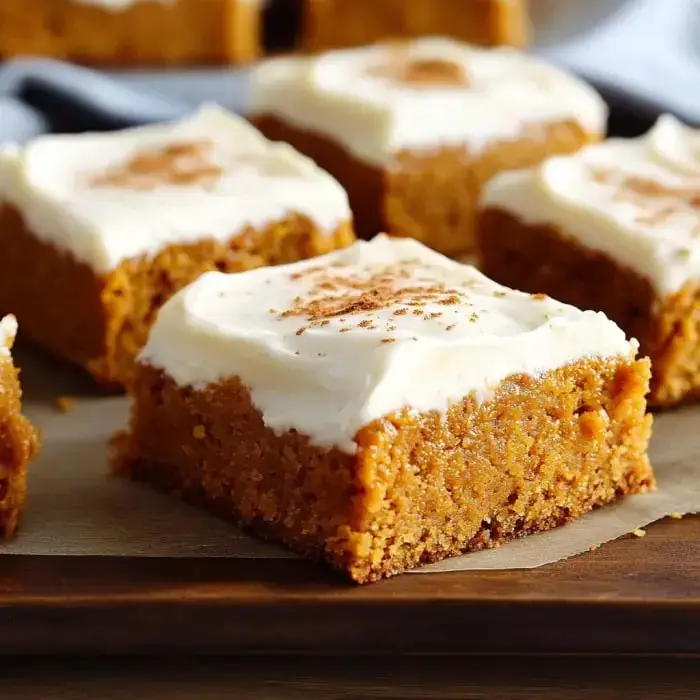 Pumpkin bars with creamy frosting and cinnamon on a wooden board, close look.