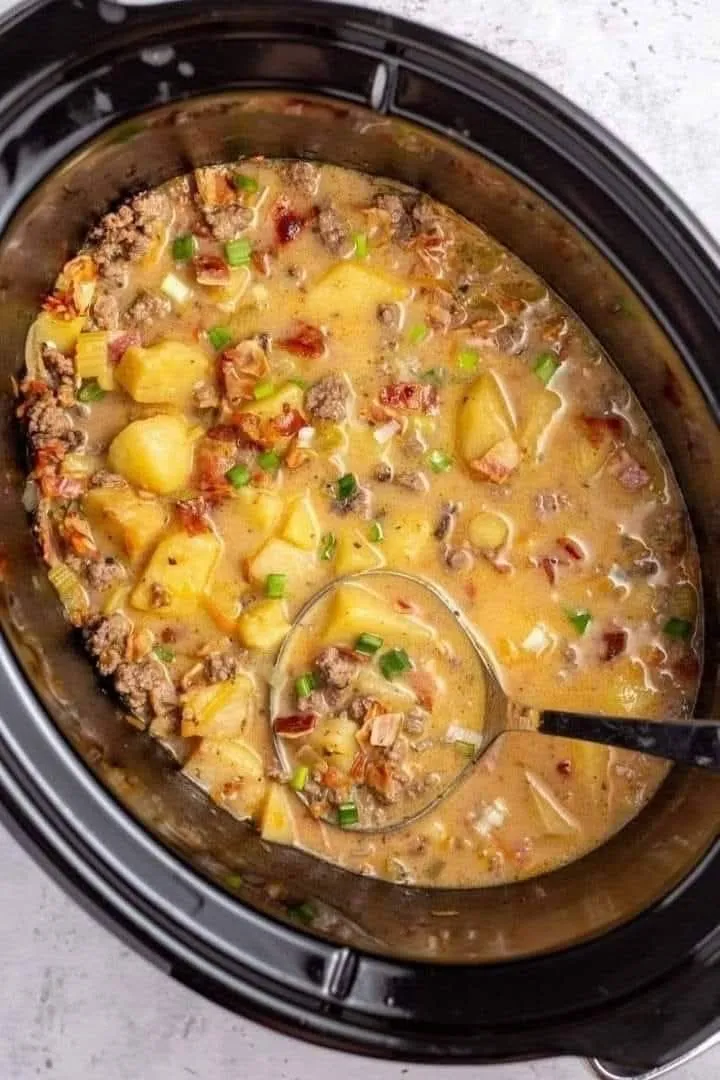 A hearty bowl of chowder with a spoon in it.