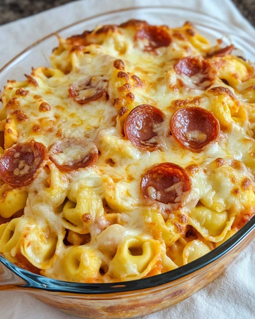A serving of pasta topped with cheese and pepperoni.