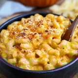 A black bowl holds baked pasta with golden breadcrumbs on top, looking creamy and satisfying.