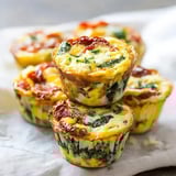 Stacked spinach and tomato egg muffins on a simple fabric background.