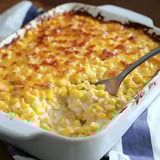 A cheesy corn dish, hot and bubbly, being served up fresh from a white casserole dish.