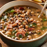 A comforting bowl of smoky black-eyed peas with bacon, sausage, and greens in a savory broth.
