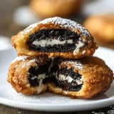 Crispy fried Oreos dusted with powdered sugar, revealing a gooey center with chocolate cookies.