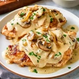 Grilled chicken breasts covered in a mushroom blend, topped with parsley and onion slices.