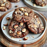 Homemade cookies with chocolate chunks, nut bits, and oats on a plate.