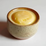 A ceramic bowl holding a yellow custard-like dessert or cream.