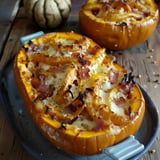 Two squash halves stuffed with cheese, bacon, and veggies served on a plate.