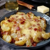 A hearty dish of golden potatoes with melted cheese and crispy bacon, served on a grey plate.